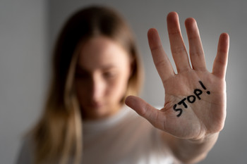 Das Bild zeigt eine Frau mit ausgestreckter Handfläche, auf der steht Stopp.