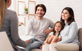 Das Bild zeigt eine Pflegefamilie mit einer Behördenmitarbeiterin.