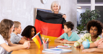 Das Bild zeigt Schülerinnen und Schüler mit ihrer Lehrerin, die eine Deutschlandfahne in der Hand hält.