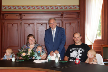 Das Bild zeigt Ministerpräsident Dr. Reiner Haseloff mit den Drillingseltern und den Kindern.